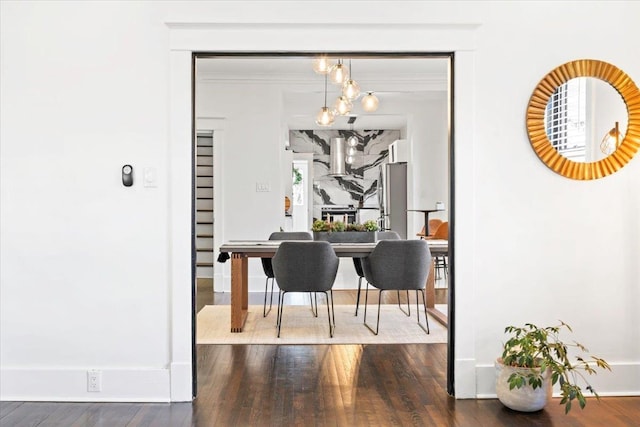 dining space with an inviting chandelier, baseboards, and wood finished floors