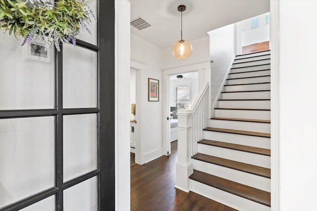 entryway with stairs, dark wood-style flooring, visible vents, and baseboards