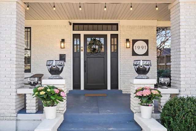 entrance to property with a porch and brick siding