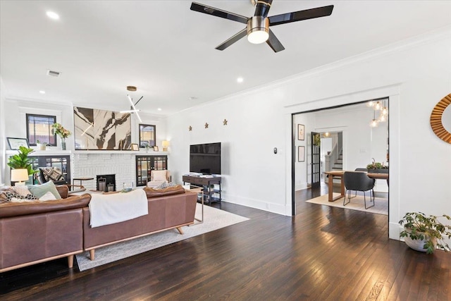 living area featuring visible vents, a fireplace, ornamental molding, and hardwood / wood-style floors