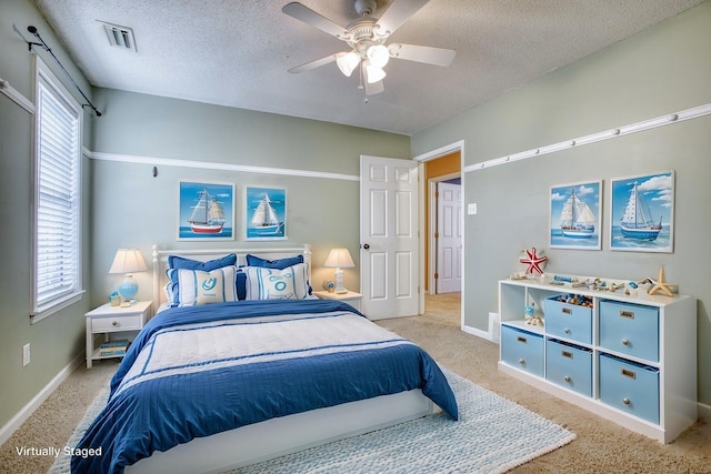 bedroom featuring multiple windows, visible vents, a textured ceiling, and light colored carpet