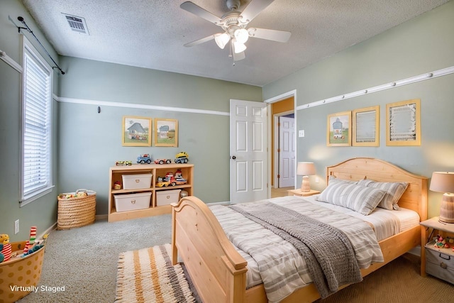 carpeted bedroom featuring visible vents, multiple windows, and a textured ceiling