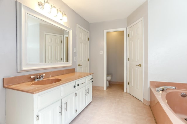 bathroom with baseboards, a garden tub, vanity, and toilet