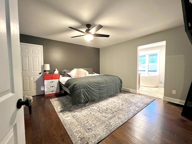 bedroom with a ceiling fan, connected bathroom, baseboards, and dark wood-type flooring