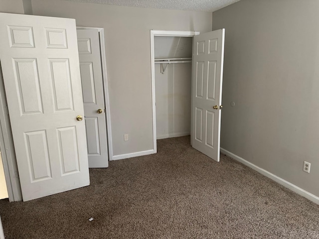 unfurnished bedroom with a textured ceiling, a closet, carpet flooring, and baseboards