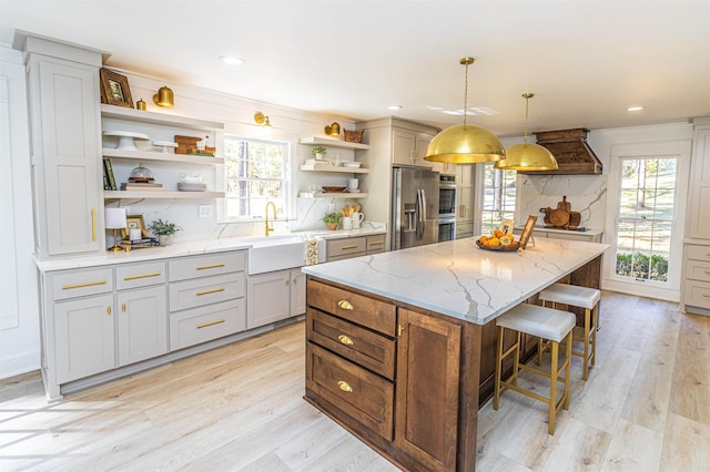 kitchen with a center island, stainless steel refrigerator with ice dispenser, open shelves, a healthy amount of sunlight, and a sink