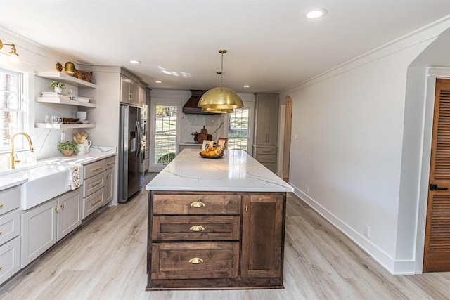 kitchen with arched walkways, stainless steel refrigerator with ice dispenser, open shelves, a sink, and premium range hood