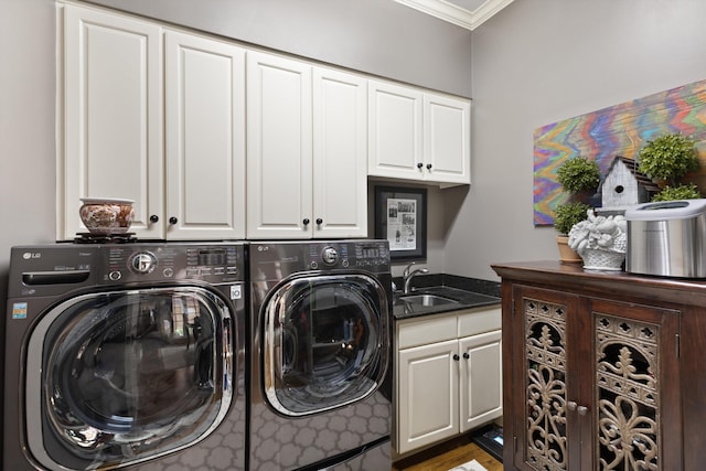 laundry area featuring washing machine and dryer, a sink, cabinet space, and crown molding