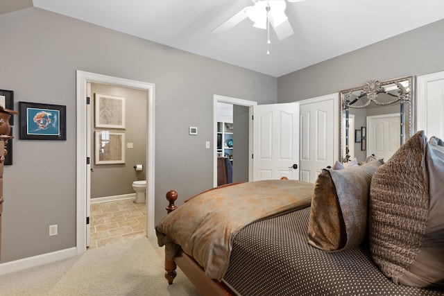 bedroom with ceiling fan, light carpet, two closets, baseboards, and ensuite bath