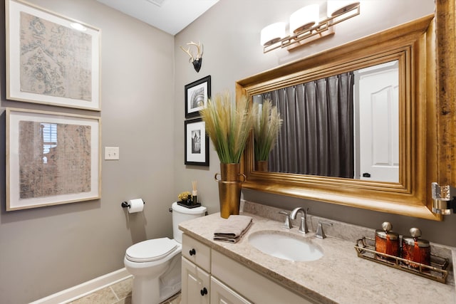 bathroom featuring baseboards, vanity, and toilet