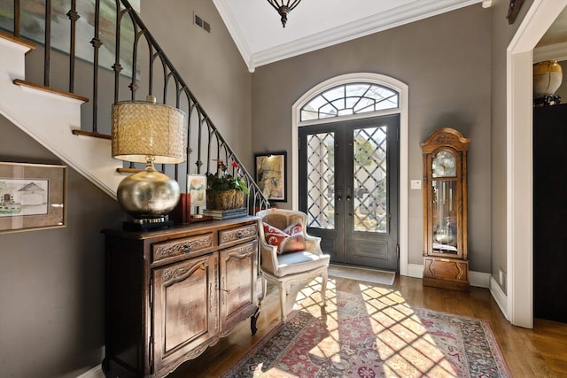 entryway featuring visible vents, stairway, ornamental molding, wood finished floors, and baseboards