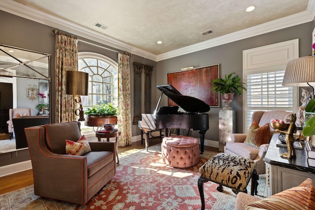 living area with ornamental molding, a wealth of natural light, visible vents, and wood finished floors