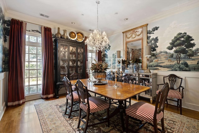 dining space featuring an inviting chandelier, visible vents, wood finished floors, and ornamental molding