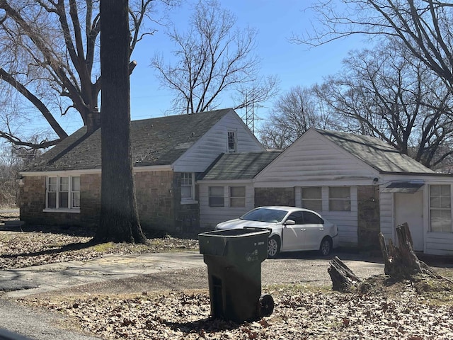 view of front of home featuring stone siding and roof with shingles