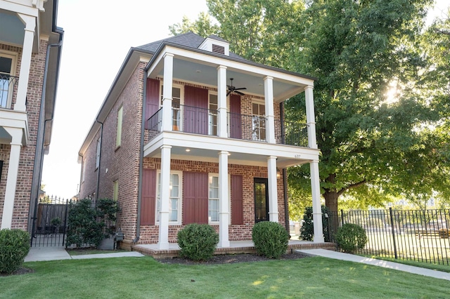 view of front facade with a balcony, ceiling fan, fence, and brick siding