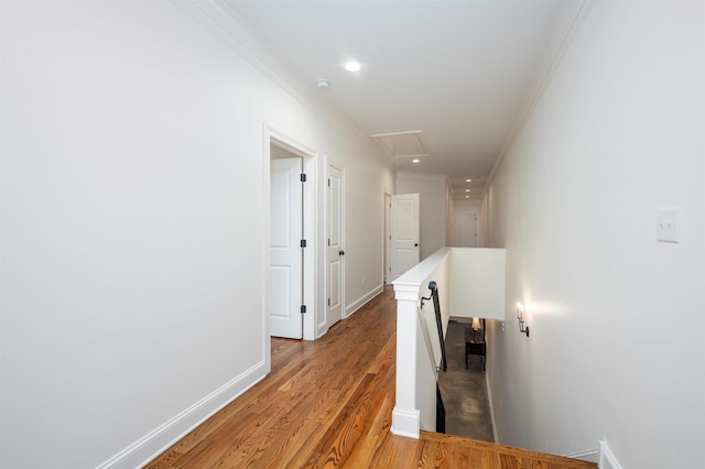 hallway featuring attic access, light wood-style floors, ornamental molding, an upstairs landing, and baseboards