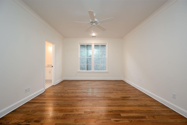 empty room with wood finished floors, visible vents, a ceiling fan, baseboards, and ornamental molding