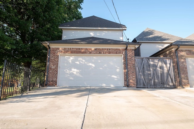 exterior space with a garage, concrete driveway, brick siding, and fence