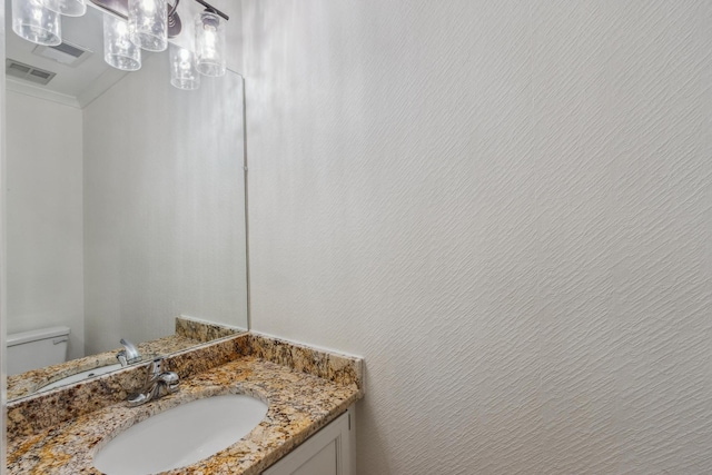 bathroom with toilet, a textured wall, vanity, and visible vents