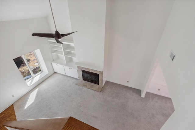 unfurnished living room featuring high vaulted ceiling, a tiled fireplace, visible vents, and light colored carpet