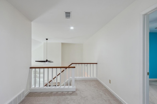 hallway with carpet, an upstairs landing, visible vents, and baseboards