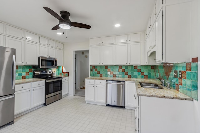 kitchen with stainless steel appliances, tasteful backsplash, a sink, and white cabinetry