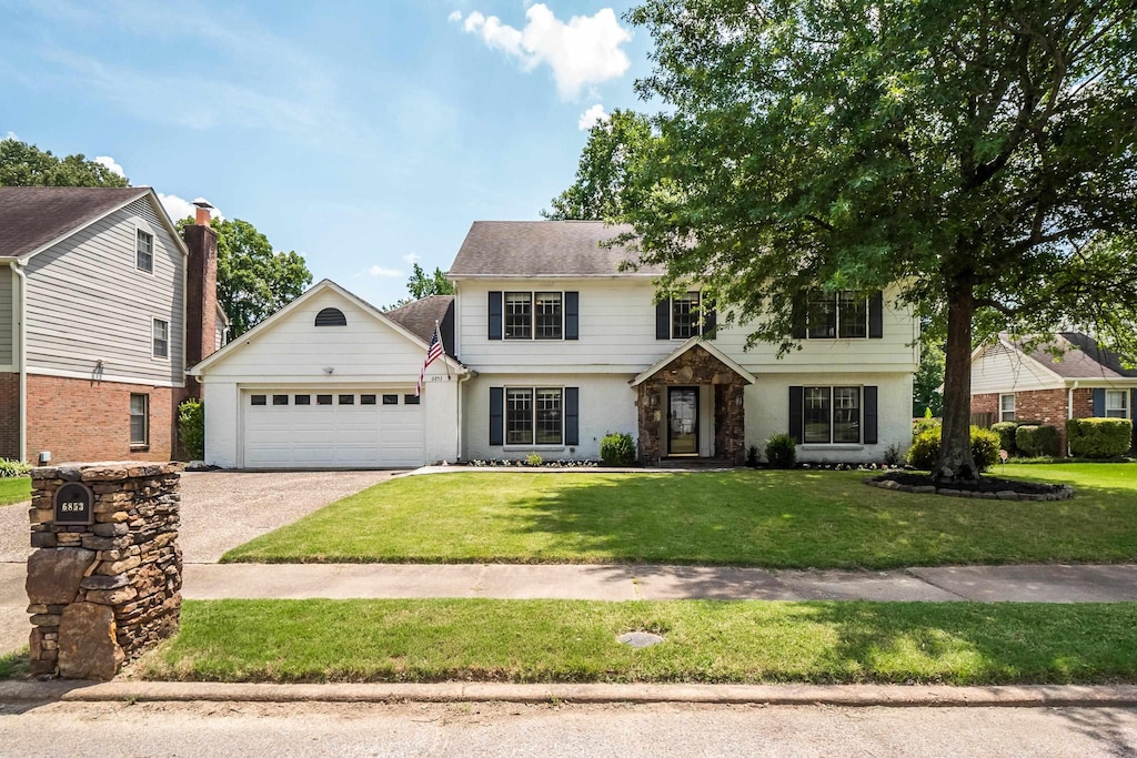 6853 Wytham Dr, Memphis, TN 38119 - colonial-style house featuring an attached garage, stone siding, a front lawn, and aphalt driveway