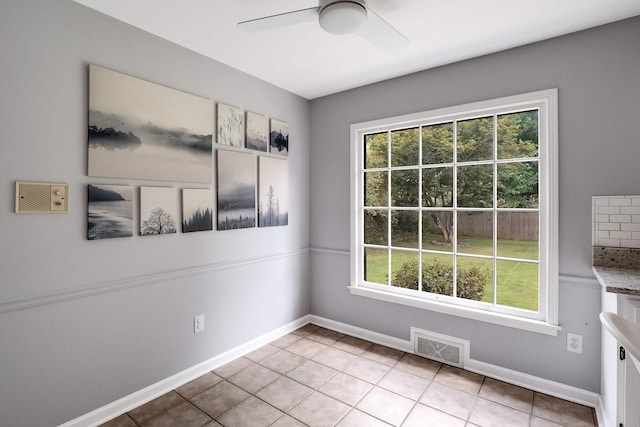 unfurnished dining area featuring a ceiling fan, visible vents, baseboards, and light tile patterned floors