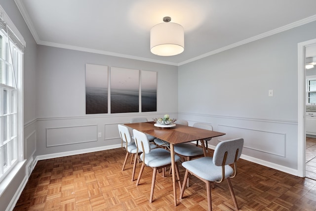 dining room featuring a wainscoted wall, a decorative wall, and crown molding