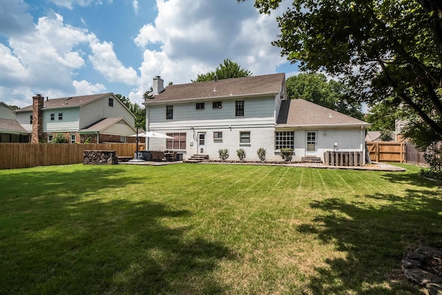 rear view of house featuring entry steps, a fenced backyard, a chimney, a yard, and a patio area