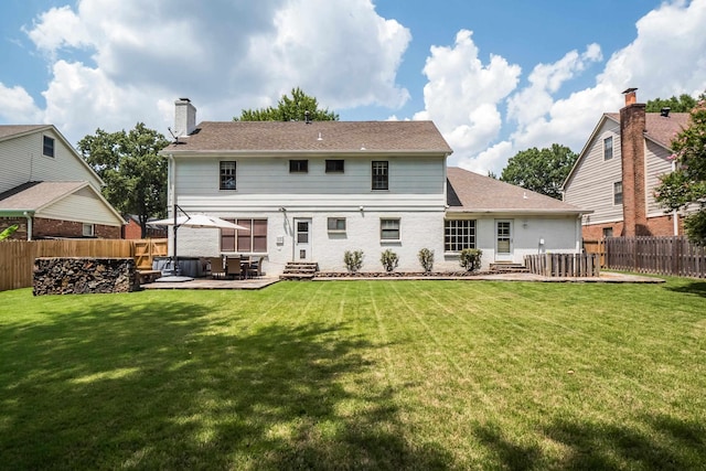 back of house featuring entry steps, a fenced backyard, a lawn, and a patio