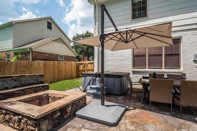 view of patio / terrace featuring a hot tub, an outdoor fire pit, fence, and outdoor dining space