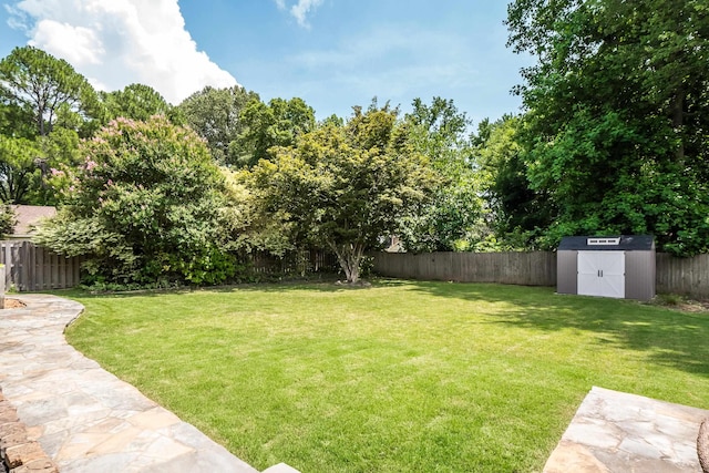 view of yard with a storage shed, a fenced backyard, and an outbuilding