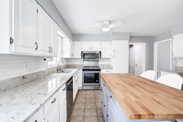 kitchen with white cabinetry, appliances with stainless steel finishes, light stone counters, and a sink