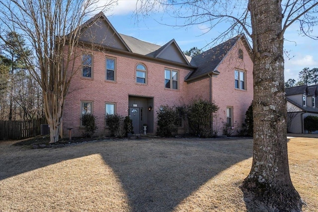 view of front of home with brick siding, fence, and central air condition unit