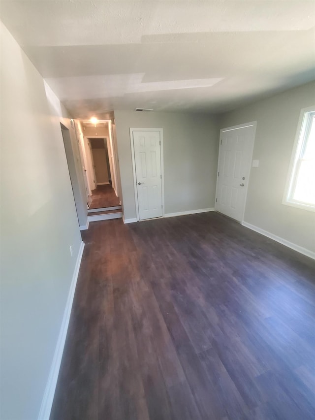 empty room with dark wood-style floors and baseboards