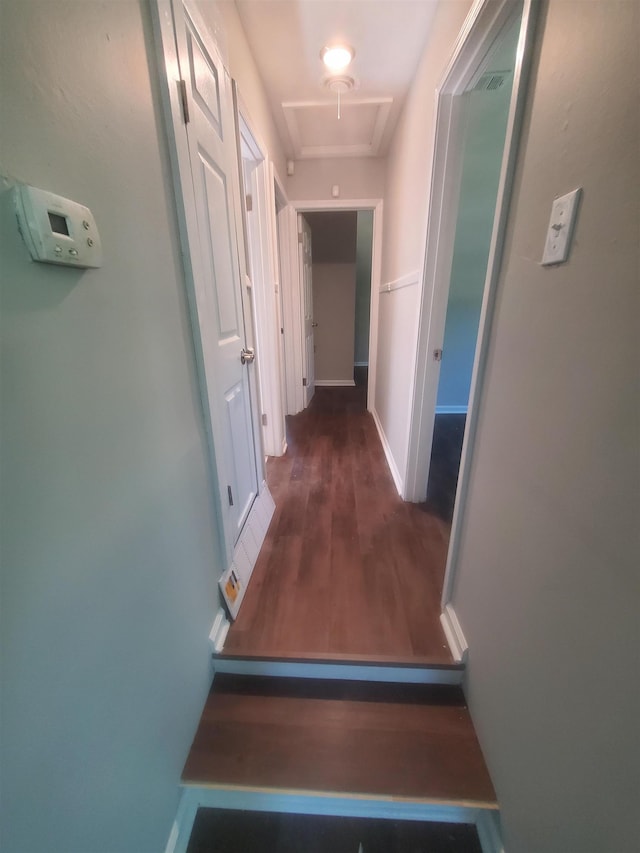 hallway featuring attic access, baseboards, and wood finished floors