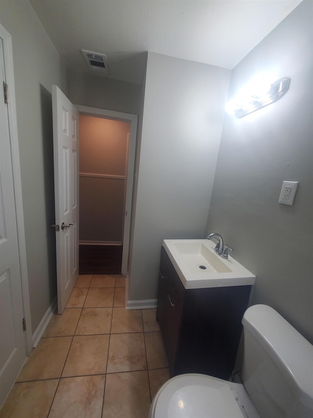 bathroom featuring baseboards, visible vents, toilet, tile patterned floors, and vanity