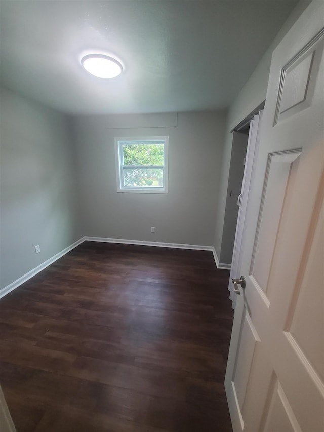 unfurnished room with dark wood-type flooring and baseboards