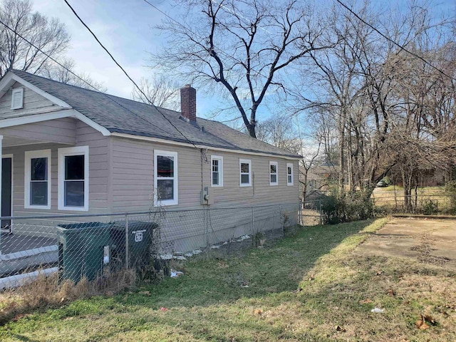 view of side of home with a shingled roof, a chimney, fence, a yard, and central AC