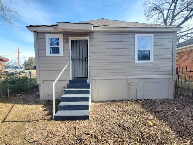 bungalow featuring a shingled roof, entry steps, and fence