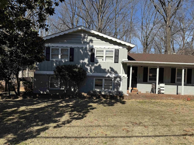 split level home featuring brick siding, a front lawn, and covered porch