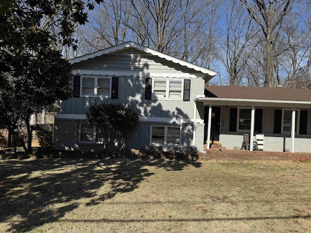 split level home featuring brick siding, a porch, and a front yard