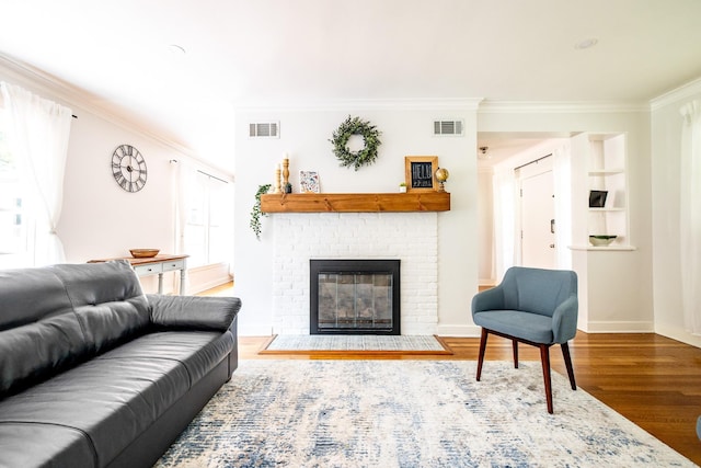 living area with a fireplace, wood finished floors, visible vents, and crown molding