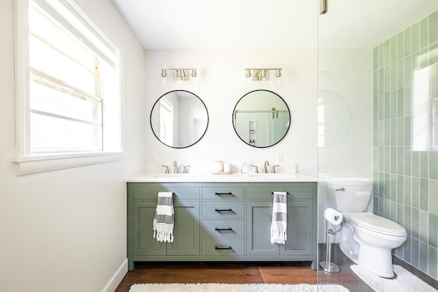 bathroom with toilet, a sink, double vanity, and wood finished floors