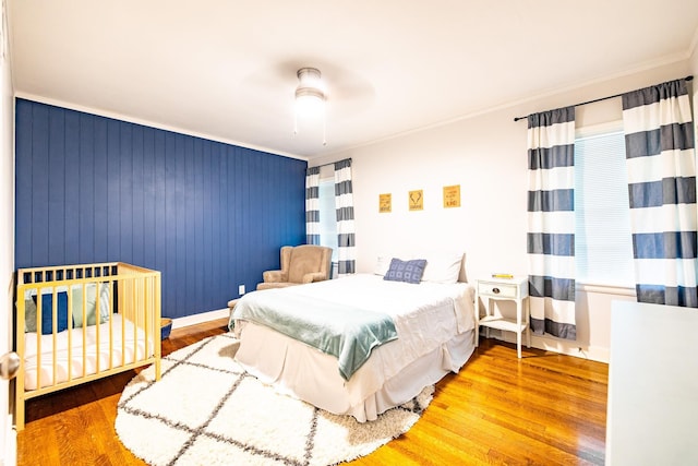 bedroom with baseboards, ceiling fan, ornamental molding, and wood finished floors