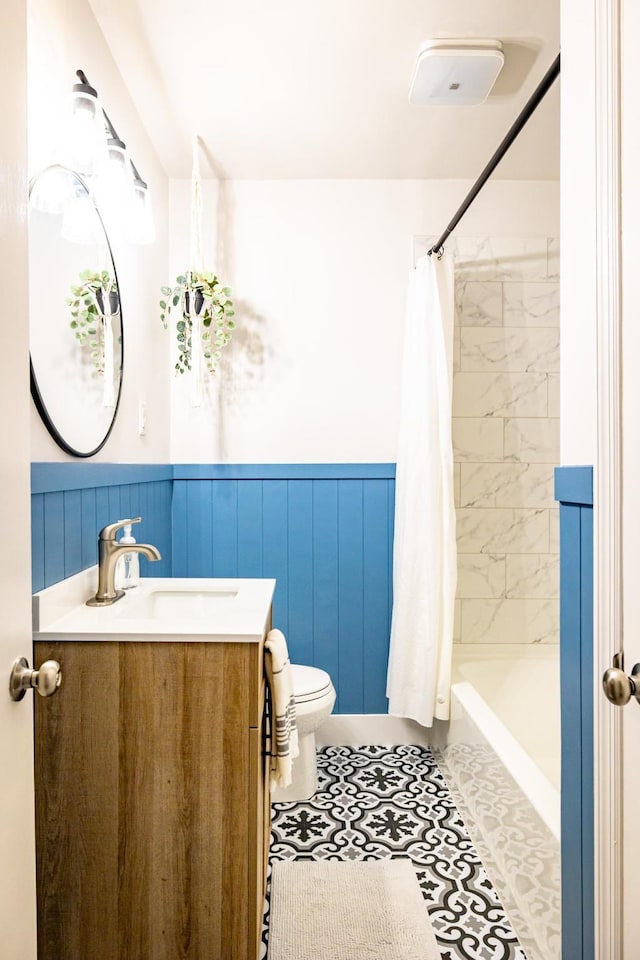 full bath with toilet, a wainscoted wall, vanity, tile patterned floors, and shower / bath combo with shower curtain