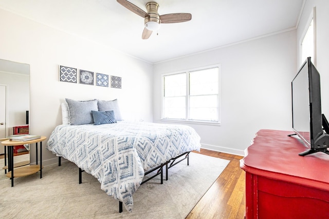 bedroom with ornamental molding, baseboards, light wood finished floors, and a ceiling fan