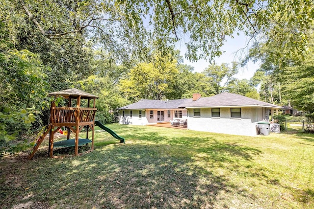 rear view of house featuring a chimney, a lawn, fence, and a playground