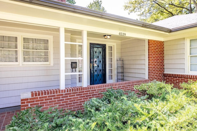 entrance to property featuring covered porch and brick siding